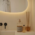 Modern Bathroom Interior With Backlit Oval Mirror White Countertop Faucet And Towel