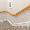 Modern Staircase With Wooden Handrail And Glass Railings Framed Pictures And Yellow Flowers
