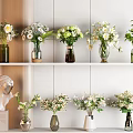 Beautiful Vases With Fresh Flowers Displayed On White Shelves And Decorative Bust Statue