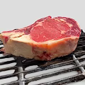 Fresh Ribeye Beef Steak On Black Grill With Juicy Red Meat And Fat