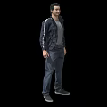 Man Standing in Black Jacket Gray T-Shirt Dark Pants and Gray Shoes on Black Background