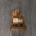 Golden Wall Lamp With Intricate Patterns Transparent Shade And Crown Design On Gray Rough Wall