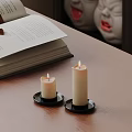 Two Lit Candle Lamps on Wooden Table with Open Book for Cozy Reading Atmosphere