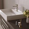 Modern White Ceramic Sink With Chrome Faucet On Dark Countertop And Flower Vase