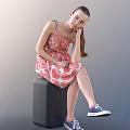 Little Girl in pink dress with white patterns sitting on black cube wearing blue sneakers