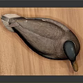 Brown Duck with Yellow Beak and Black Head on Wooden Board against Gray Background