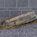 Natural Stone with Rustic Wooden Base on Gray Floor Against Gray Tiled Wall