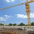 Construction Site With Tower Crane Blue Sky White Clouds Wooden Planks Bricks And Green Trees