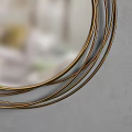 Round Gold Framed Mirror With Multiple Layers Of Lines On Gray Background