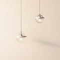 Two Transparent Glass Globe Pendant Lights Hanging With Metal Ring On Light Colored Background