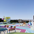 Colorful Children's Play Area Featuring Circular Structures Decorative Mushroom Shapes Vibrant Ground Patterns And Greenery