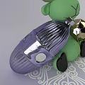 Green Doll With Black Feet Holding Purple Metallic Decorative Ball On White Patterned Background