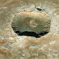 Aerial View Of Large Circular Meteor Crater In Desert Landscape With Central Depression And Surrounding Terrain