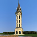 Ornate Tiered Tower With Spire And Arched Windows Against Blue Sky With Greenery