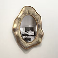 Golden Irregular Shaped Mirror Hanging On White Wall Reflecting Living Room Interior