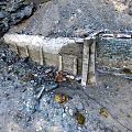 Stone Tunnel Entrance in Mountainous Terrain With Rocks Snow Patches and Slope Path
