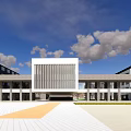 Modern School Building With White Exterior Wooden Structure And Reflection Pool Under Blue Sky