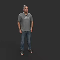 Man Standing in Dark Background Wearing Gray Polo Shirt Blue Jeans and Black Shoes