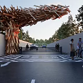 Artistic Entrance Gate Featuring Wooden Stick Structure Trees Driveway And Pedestrians