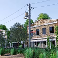 Old Brick Building Covered With Vines Surrounded By Trees And Electric Pole Under Blue Sky