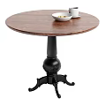 Round Wooden Dining Table With Black Carved Base White Bowl And Cups On Top