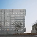 Modern Office Building With Glass Facade Surrounded By Trees On City Street And Parked Cars