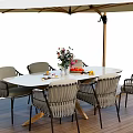 Outdoor Table with Woven Chairs Flower Vase Fruits and Umbrella on Wooden Deck