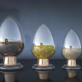 Three Transparent Teardrop Shaped Ceramic Vessels With Golden Base And Decorative Granules