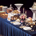 Elegant Dessert Table Setup With Assorted Cakes Cookies Flowers Candles And Blue Tablecloth