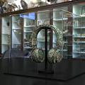 Ancient Bronze Earring Sculpture With Intricate Carving In Transparent Museum Display Case