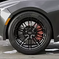 Car Tire With Black Alloy Wheels Red Brake Calipers And Tread Pattern On Wooden Deck