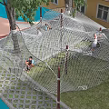 Kindergarten Outdoor Playground Featuring Climbing Net Structure With Children Playing In Green Grass