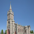 Classic European Church Architecture With Clock Tower Spire Stone Facade Arched Doorway And Trimmed Shrubs