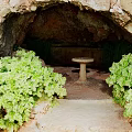 Natural Cave Landscape With Lush Green Plants Stone Pathway And Round Stone Table