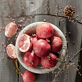 Rustic Ceramic Bowl Filled With Fresh Pomegranates Sliced Sections And Natural Decorative Branches