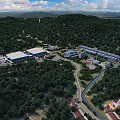 Aerial View of Industrial Factory Surrounded by Lush Forests River and Mountain Backdrop