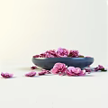Fresh Pink Flowers in Blue Bowl with Scattered Petals on Light Surface