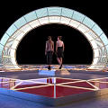 Event Entrance with Arched Lighting Structure and Reflective Geometric Floor Design where Two People Stand