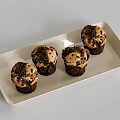 Four Chocolate Cupcakes With Cream Frosting And Chocolate Crumbs On White Rectangular Tray