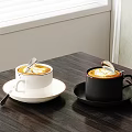 Coffee Drinks in White and Black Cups with Latte Art on Wooden Table and Spoons