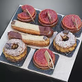 Assorted Delicious Pastries With Chocolate Glaze And Decorative Leaves On Tray