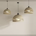 Three Beige Pendant Lights With Gold Wavy Patterns Hanging Against White Wall