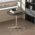 Round Black Top Side Table with Silver Metal Base Wheels and Decorative Items Near Bookshelf