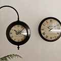 Two Black Decorative Clocks With Roman Numerals On Light Colored Wall