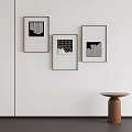 Three Black Framed Abstract Paintings on White Wall Featuring Geometric Patterns and Brown Round Table 3d model