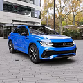 Blue Volkswagen SUV Parked on Brick Pavement With Modern Buildings and Trees