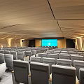 Modern Conference Room With Wooden Geometric Ceiling Gray Seats Warm Lighting And Large Blue Screen