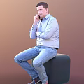 Man In Blue Shirt And Jeans Sitting On Chair With Crossed Arms Hand On Chin
