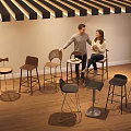 Various Stylish Bar Stools Displayed In Modern Showroom With Wooden Floor And People Seating