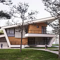 Modern Single Family Villa With Sloped Roof Wooden Elements And Lawn Surrounded By Trees